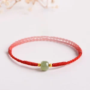Handmade jade lucky bead bracelet with red braided cord and gold spacers, side angle view