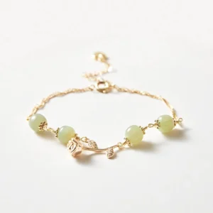Close-up detail of smooth Hetian jade beads and delicate rose flower charm on gold chain
