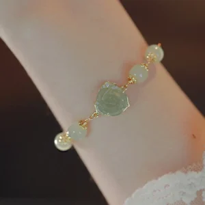 Side angle view of Hetian jade rose bracelet on wrist with lace cuff, displaying delicate chain and jade beads