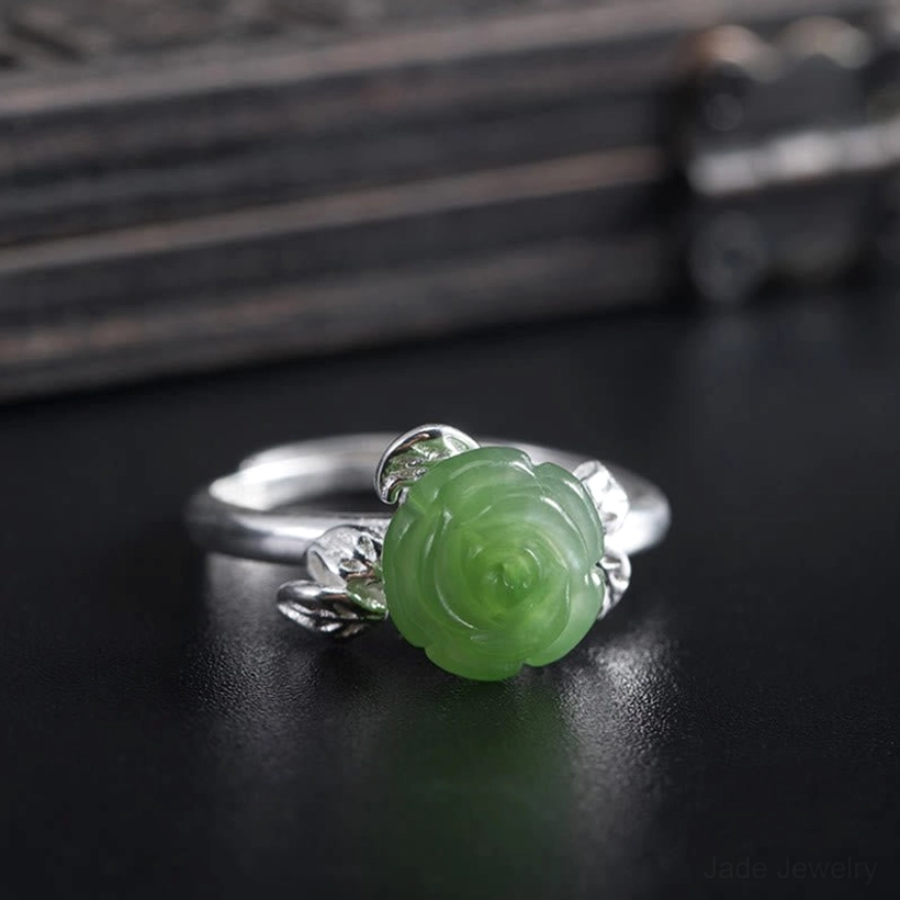 Front view of hand-carved jade rose inlaid in sterling silver decorative leaf setting