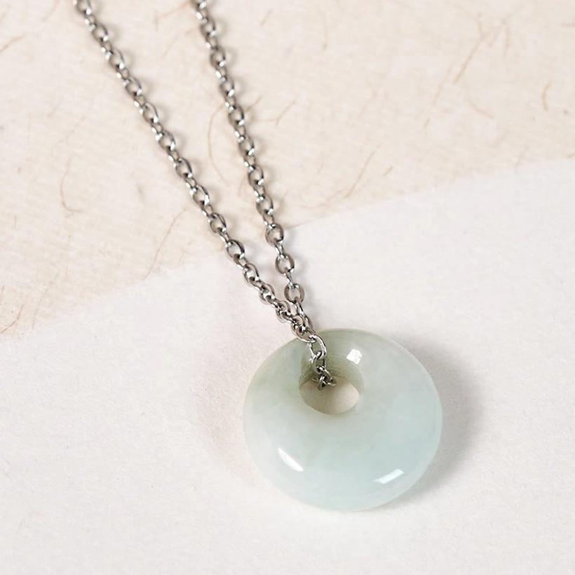Silver chain jade pendant necklace flat lay on light paper background clean display