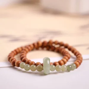 Close-up flat lay of double wrap jade bracelet displaying brown wooden beads with jade tube spacer and accent beads