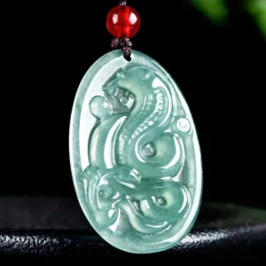 Light cyan carved jade snake pendant on black display stand, detailed 3D carving with red bead