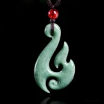 Natural green jade spiral flame pendant necklace front view on black background, handcrafted prosperity charm