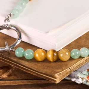 Close-up side view of polished jade and gemstone beads showing natural stone details and metallic accents on wooden desk