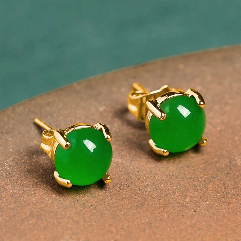 Round natural jade stud earrings with gold-plated 925 sterling silver four-prong setting on brown background