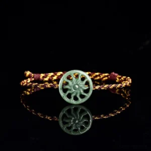 Green jade sun carved pendant on bicolor braided rope bracelet, top-down front view showing mirrored reflection