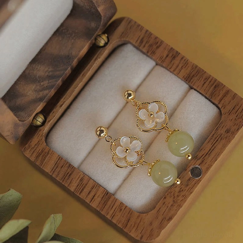 Complete set of jade tridacna flower drop earrings displayed in open wooden jewelry box, full width view