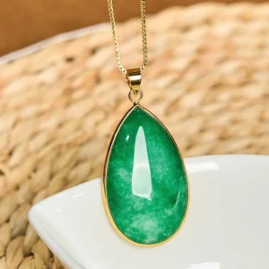 Close-up of polished green jade water drop pendant showing natural marbling and gold hardware