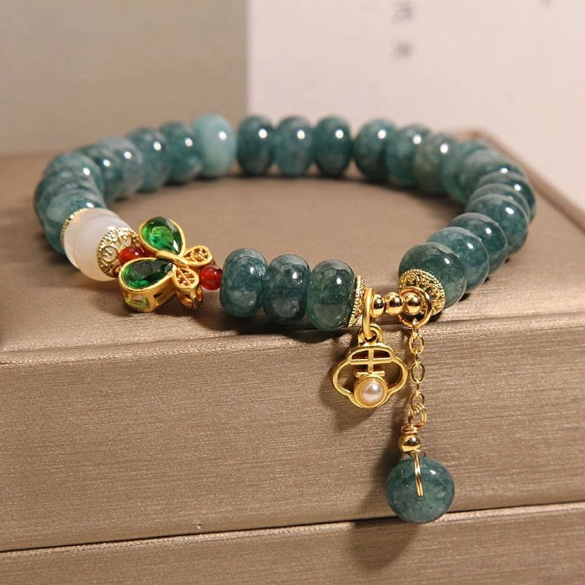 White agate accent bead jade bracelet arranged neatly in brown jewelry display box, top-down perspective