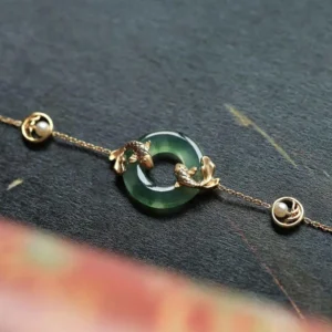 Close-up detail of golden koi fish charm on jade bracelet with pearl-studded chain