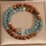 Kuka Seed and Jade prosperity bracelet in luxury gift box, featuring mixed blue jade beads, natural brown wooden kuka seeds, white jade pendant, and gold spacers - top view