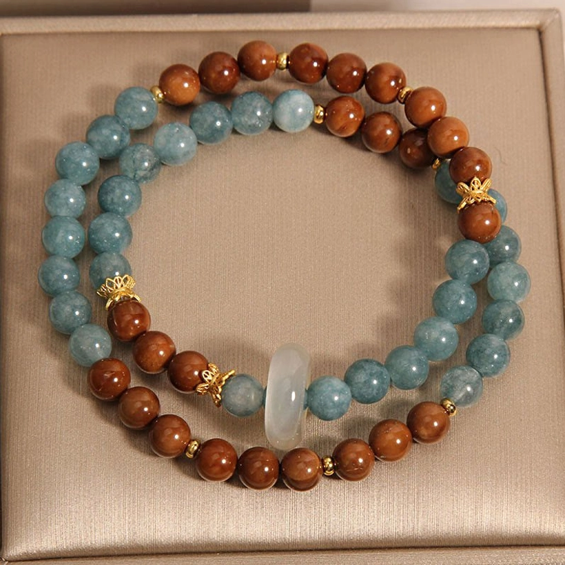 Kuka Seed and Jade prosperity bracelet in luxury gift box, featuring mixed blue jade beads, natural brown wooden kuka seeds, white jade pendant, and gold spacers - top view
