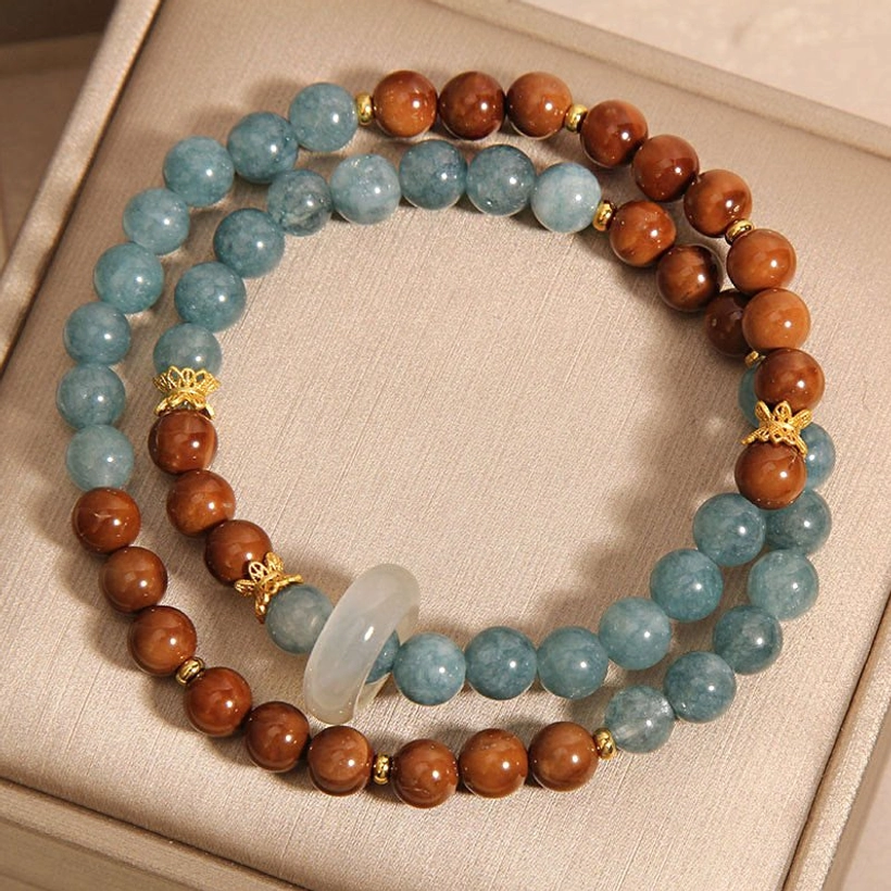 Kuka Seed Jade prosperity bracelet featuring natural brown wooden seeds, blue jade beads, white jade accent, and gold spacers - detail shot