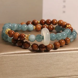 Double-strand Kuka Seed Jade luck bracelet stacked display showing side profile with alternating brown and blue beads, white jade donut charm, and detailed bead work