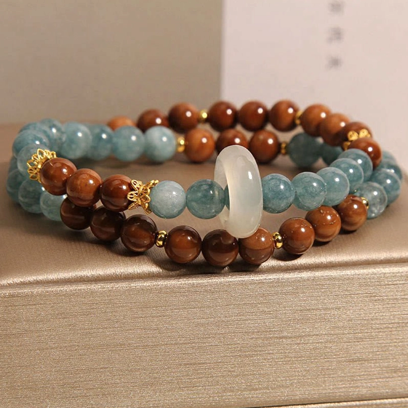 Double-strand Kuka Seed Jade luck bracelet stacked display showing side profile with alternating brown and blue beads, white jade donut charm, and detailed bead work