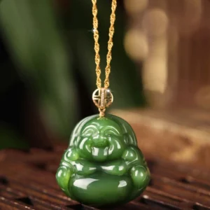 Laughing Buddha cyan jade pendant necklace with 925 silver and 18K gold clasp displayed on wooden surface with natural green foliage background