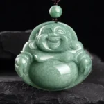 Laughing Buddha cyan jade pendant necklace close-up front view showing intricately carved Maitreya Buddha smiling face on dark stone background