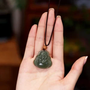 Close-up of Laughing Buddha jade pendant in palm, displaying intricate hand-carved smiling Buddha face on smooth polished cyan jade
