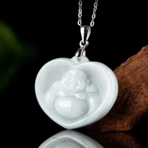 White jade Maitreya Buddha heart pendant necklace shown from front side angle with green foliage and wood decor