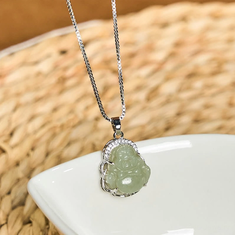 Carved light green Hetian jade Laughing Buddha pendant necklace, oblique front view on ceramic plate