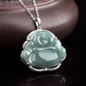 Green jade Buddha pendant with silver bezel frame and diamond inlay accents, overhead detail view on dark reflective background