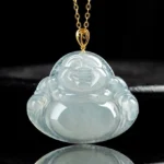Laughing Buddha natural jade pendant close-up front view on black display, showing detailed carved smiling Buddha face with translucent light green jade and gold-tone metal bail