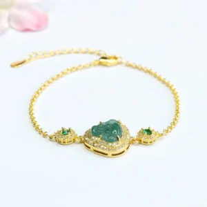 Laughing Buddha green jade bracelet with zircon accents on pink floral background, top-down flat lay view