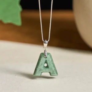 A-shaped green jade pendant necklace with slim sterling silver chain flat lay with leaf decor