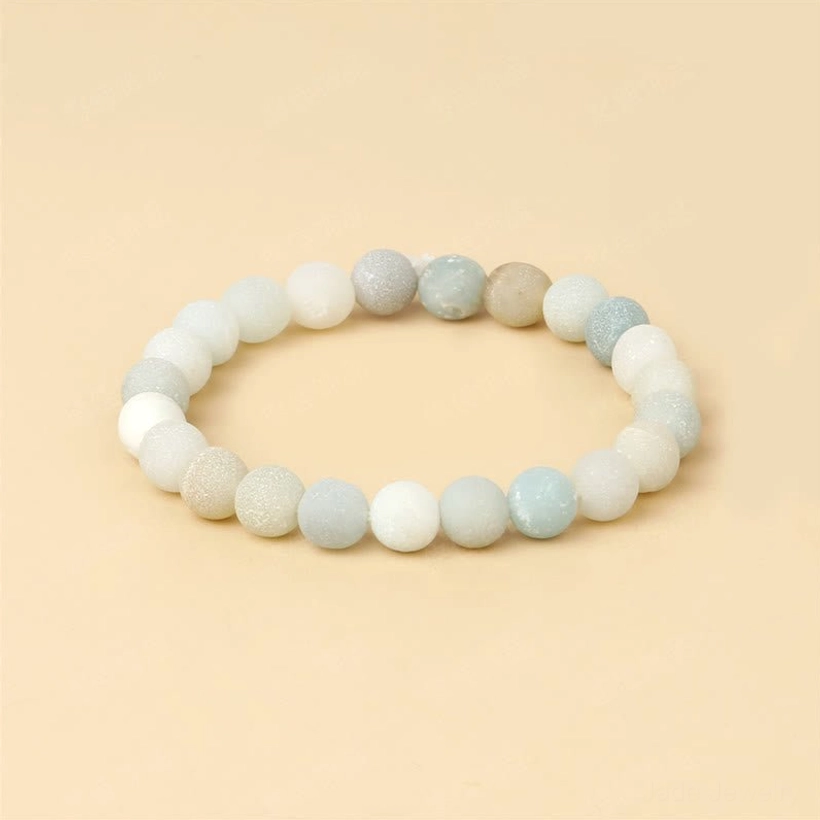 Light amazonite jade balance bracelet flat lay overhead, warm beige background showing gradient beads from off-white to light green