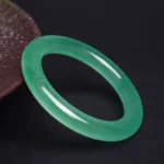 Natural light green jade bangle bracelet shown from side angle, displaying smooth polished surface and authentic translucent jade stone
