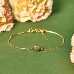 Gold-plated sterling silver jade bead bracelet with light green jade, top-down flat lay with green and pink florals