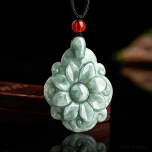 Light green hand-carved jade flower pendant necklace with red bead accent displayed on dark wooden background, showing intricate Kalanchoe blossom design for prosperity and abundance