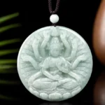 Light green jade thousand-hand Guanyin pendant displayed on green leaf background with dark cord
