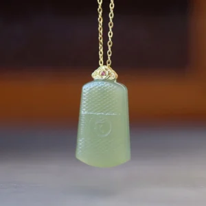 Light pale green Hetian jade Om necklace with engraved Om symbol and sterling silver setting, overhead product shot