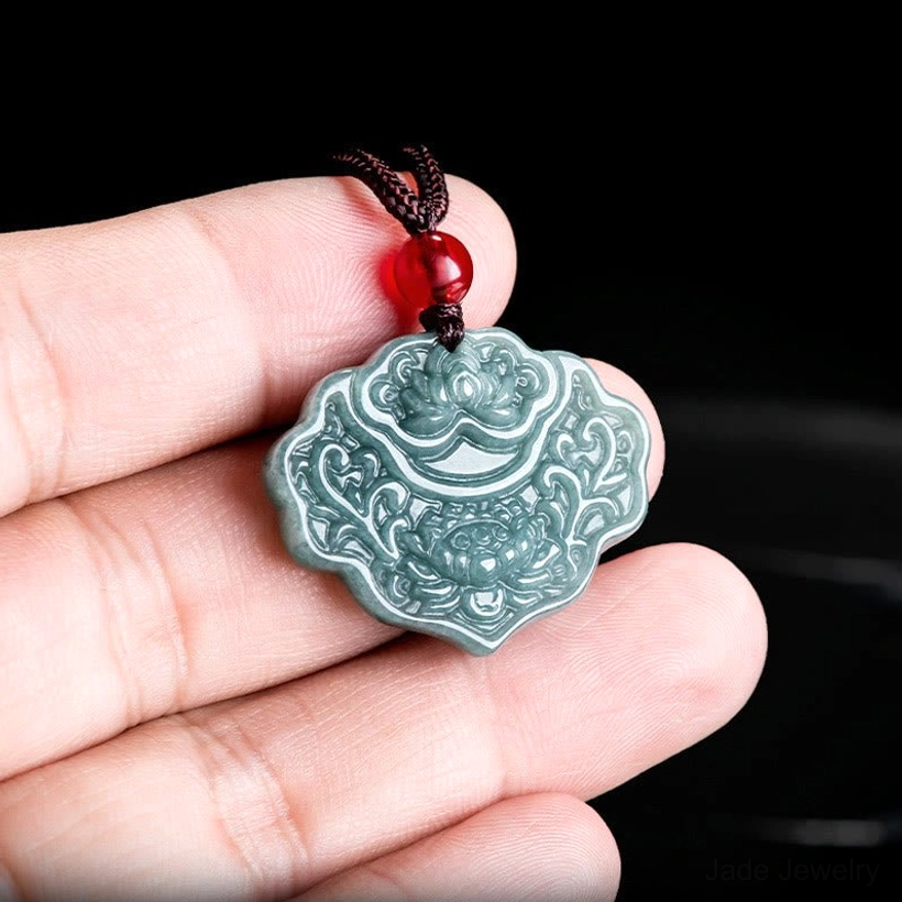 Person holding celadon jade lotus pendant necklace showing pendant size and carved details