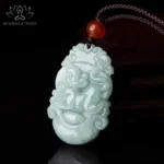 Monkey Chinese zodiac jade pendant necklace with red agate bead and brown cord on dark background