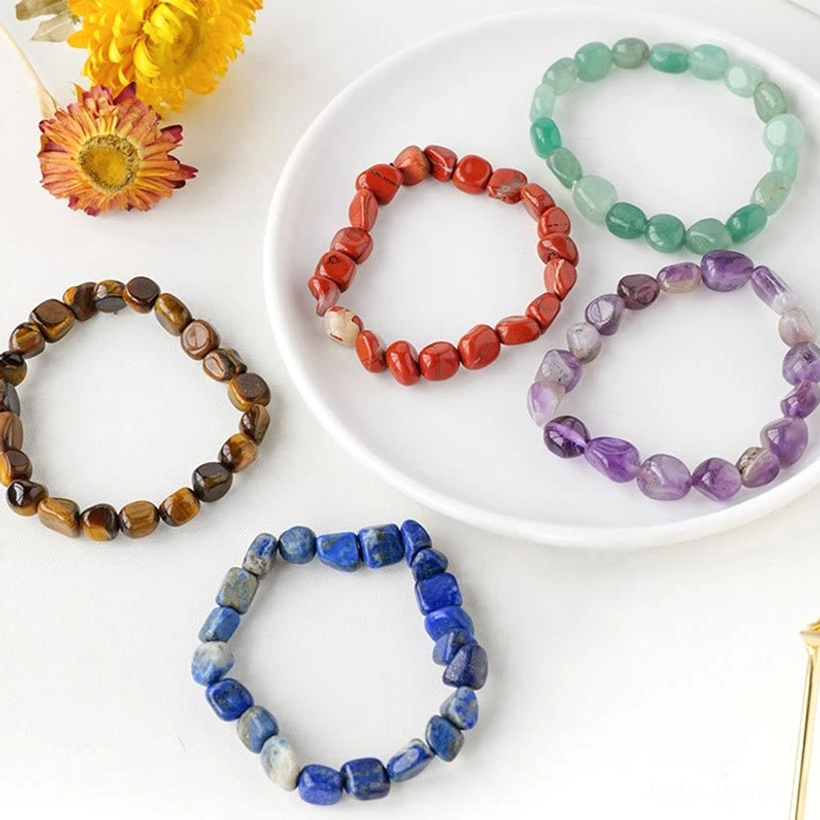 Assorted colorful crystal beaded bracelets flat lay with dried flower decorations on white background