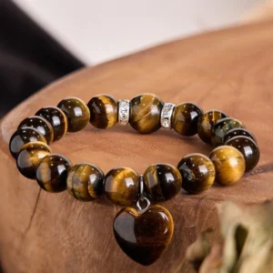 Multi-stone heart chakra bracelet with green aventurine, white jade, clear crystal, pink crystal, tiger eye and unakite beads displayed on dark wooden surface