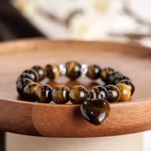 Six-stone healing bracelet with heart pendant charm flat lay on wooden tray showing green aventurine and white jade beads