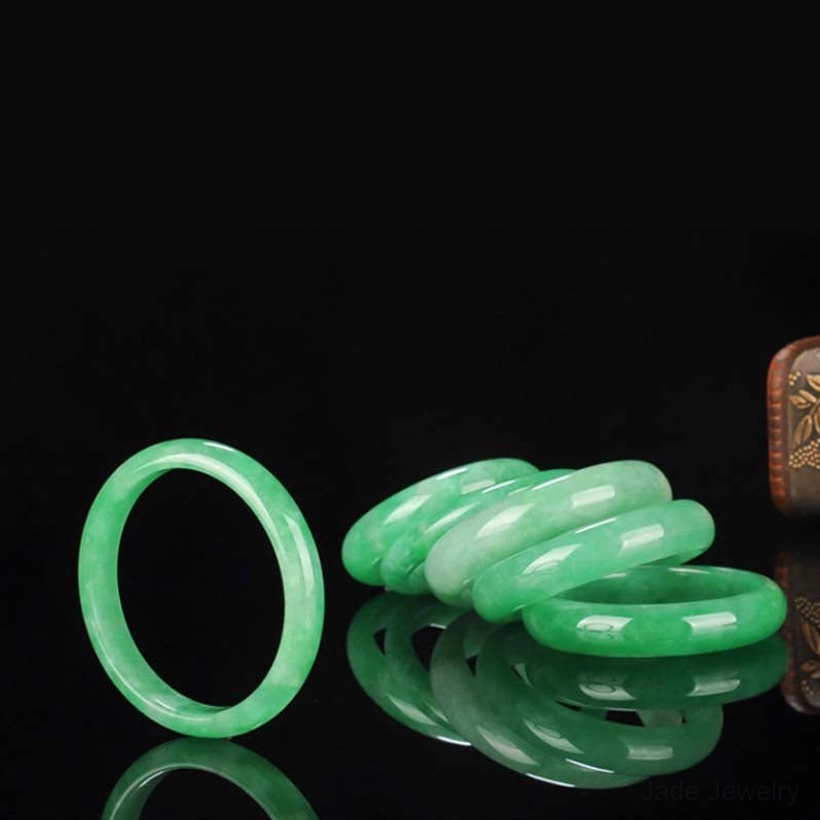 Multiple sized natural jade bangle bracelets arranged overhead, displaying variety of jade colors and smooth polished craftsmanship