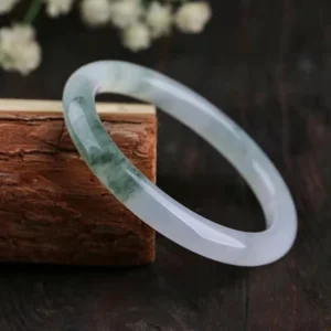 Authentic jade bangle showing side profile with green streaky inclusions and translucent finish