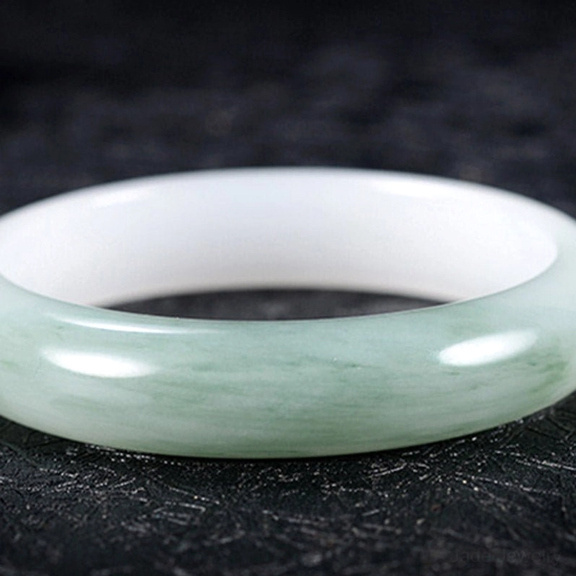 Wide jade bangle flat overhead view showing mixed white and green natural marbling with polished finish
