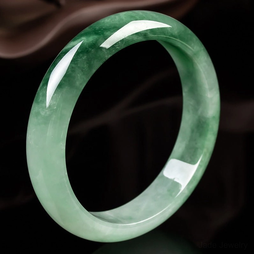 Natural jade bangle bracelet with gradient green and dark veining, polished finish, close-up overhead view