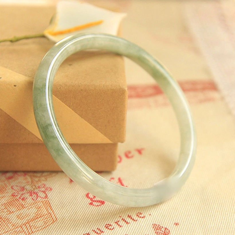 Variegated green jade bangle bracelet with natural patterns and polished finish shown in three-quarter side view