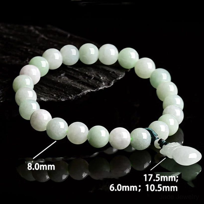 Thick jade bead bracelet on dark stone background flat lay, clearly showing individual bead sizes and carved jade drop pendant detail