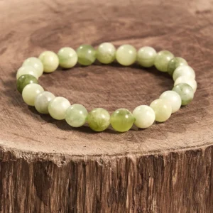 Authentic jade beaded bracelet with mixed light and dark green stones on tree stump, natural jade bracelet for good fortune