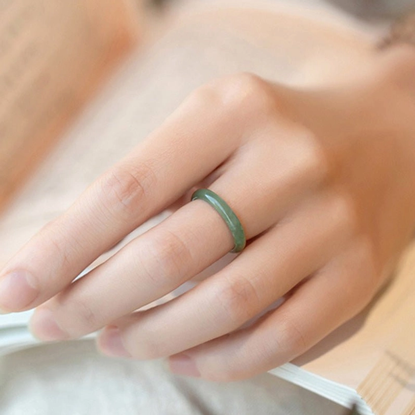 Light green jade prosperity ring worn on finger casual reading lifestyle scene
