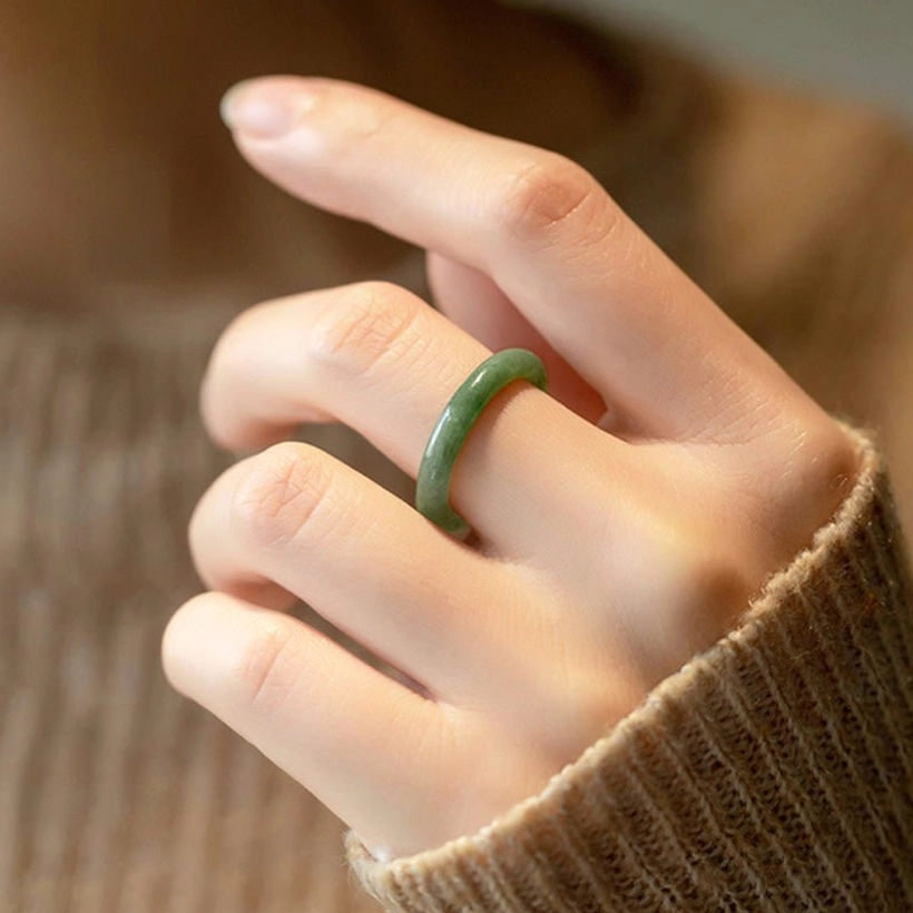 Dark green natural jade prosperity ring worn on hand lifestyle sweater background