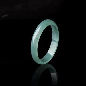 Natural jade prosperity ring handcrafted jadeite band side angle view with reflective backdrop